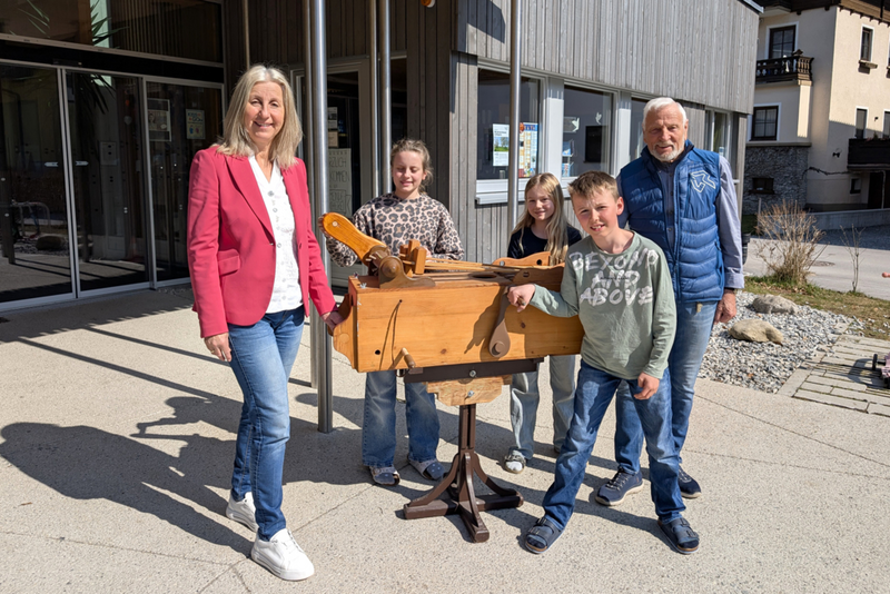Direktorin Sonja Zechner und Wilhelm Kleine präsentieren mit Kindern die eigene Schul-Osterratsche.