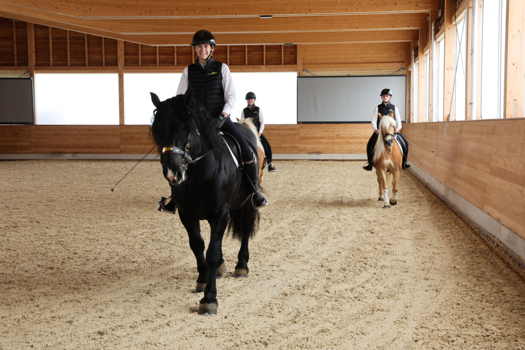 Reiterin auf einem schwarzen Pferd in der neuen Reithalle der LFS Winklhof